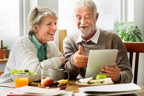 Oudere vrouw en man kijken naar een tablet