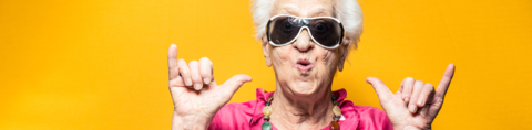 Oudere vrouw met zonnebril met armen in de lucht