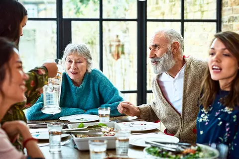 6 mensen zitten aan tafel te eten