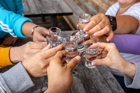 6 mensen klinken met shotglaasjes